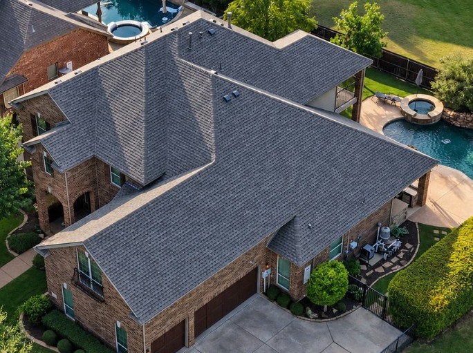 Professional drone photo from the side of a high-end home with a brand new roof replacement completed by American National Roofing