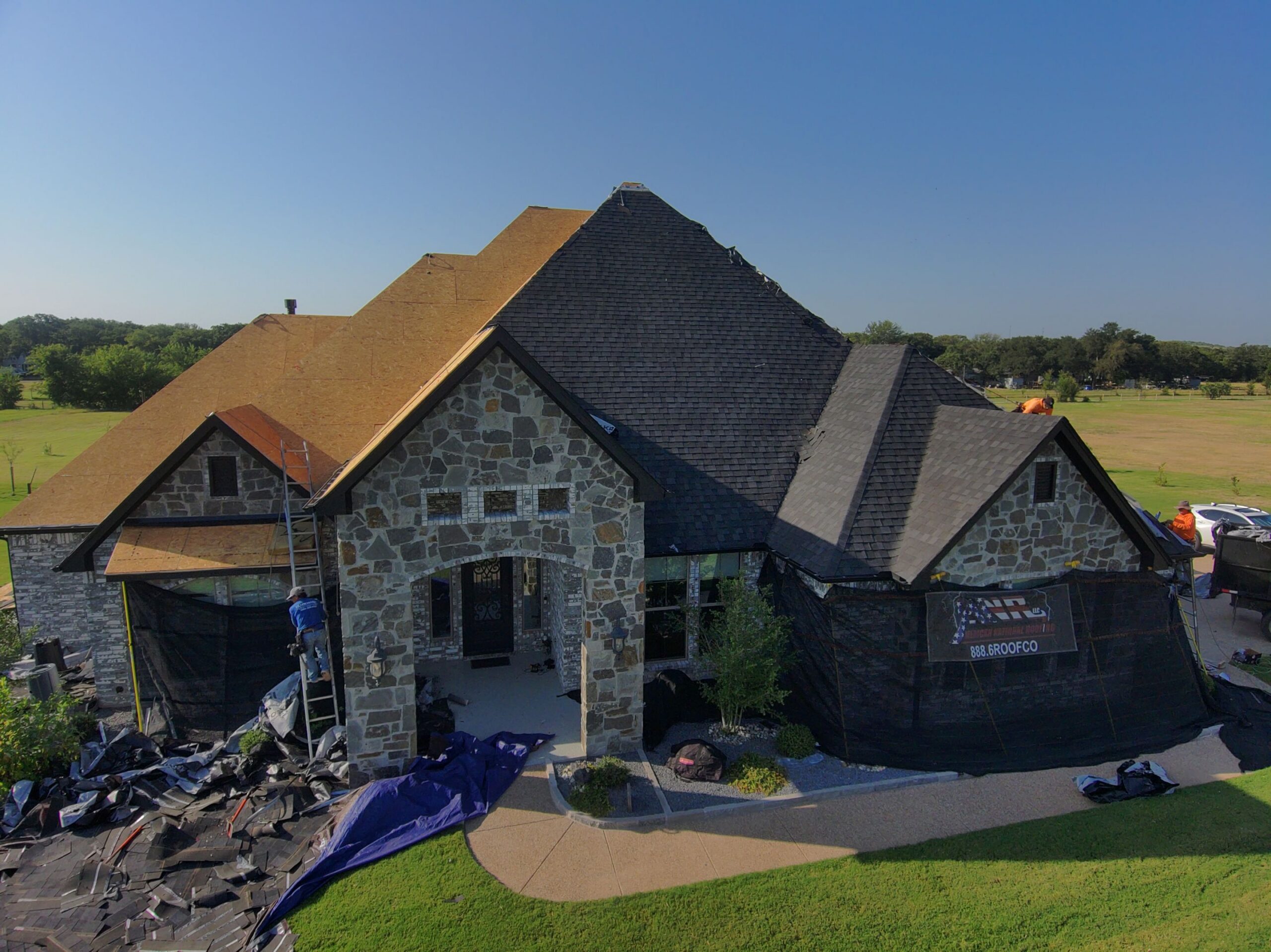Professional front view of the entire house during a roof replacement, showing the exposed wood decking.